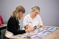 Two white women staring at the board game on a flat surface