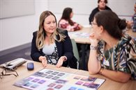 Two white women having a discussion in a room with a board game on the table