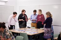 A group of five people standing around a table and having a discussion