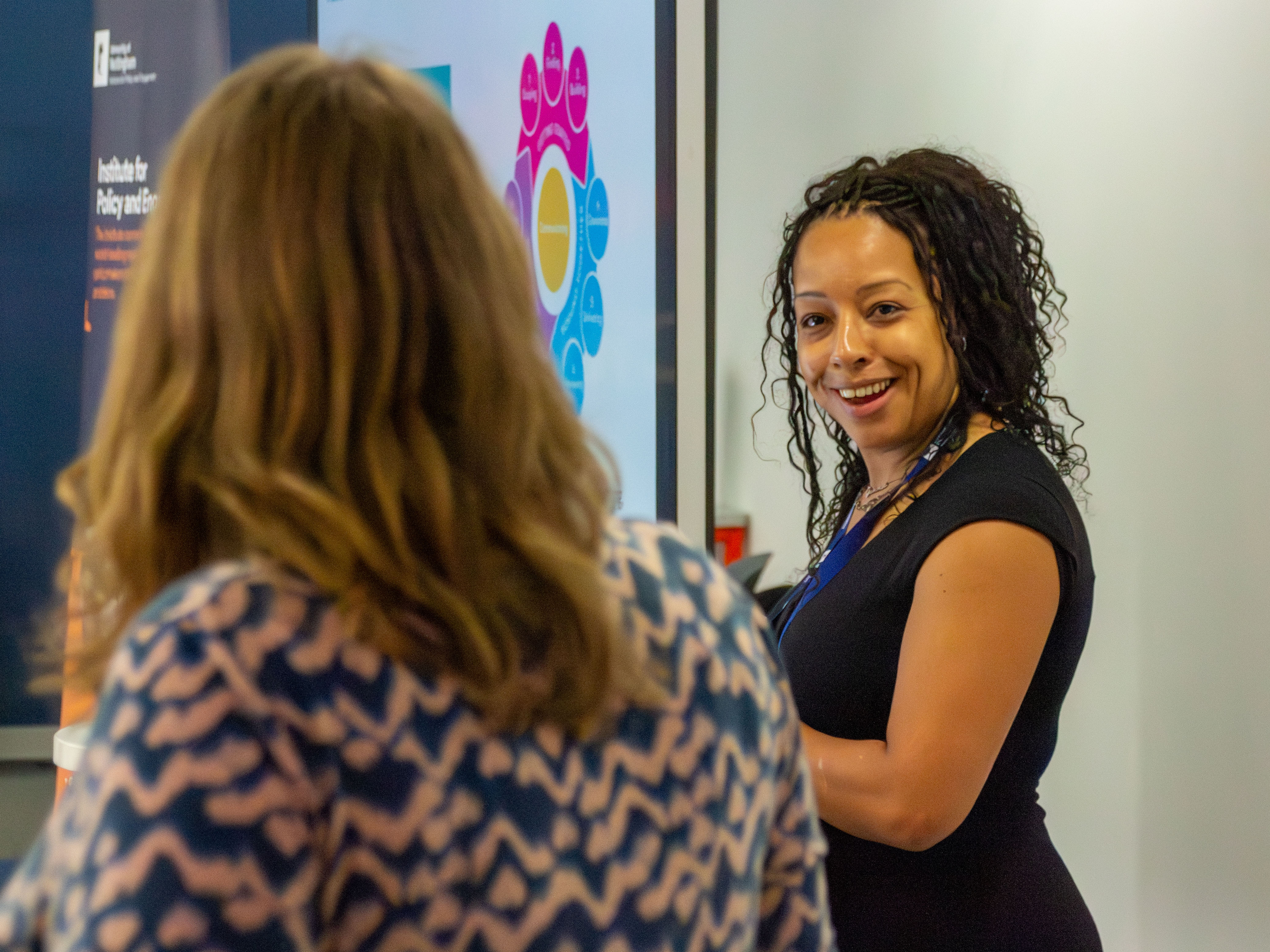 Two women talking in front of a colourful screen