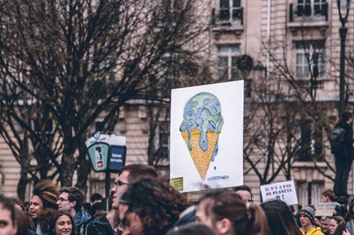 Placard above a crowd showing a melting ie cream cone painted to look like the Earth is melting