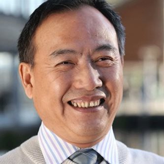 Headshot of an asian man in a suit smiling 