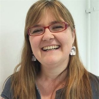 Headshot of a white woman smiling in glasses
