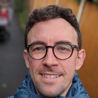 Headshot of a white man in glasses smiling 