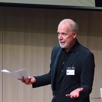 white man in a suit giving a lecture