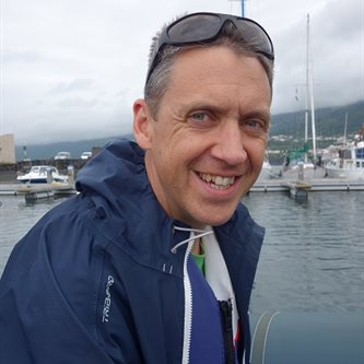 Photo of a white man smiling on a boat in a raincoat