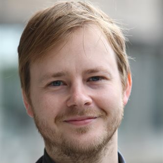 White man in a suit smiling 