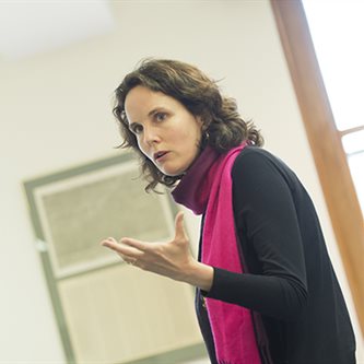 Photo of a white woman in a pink scarf giving a lecture