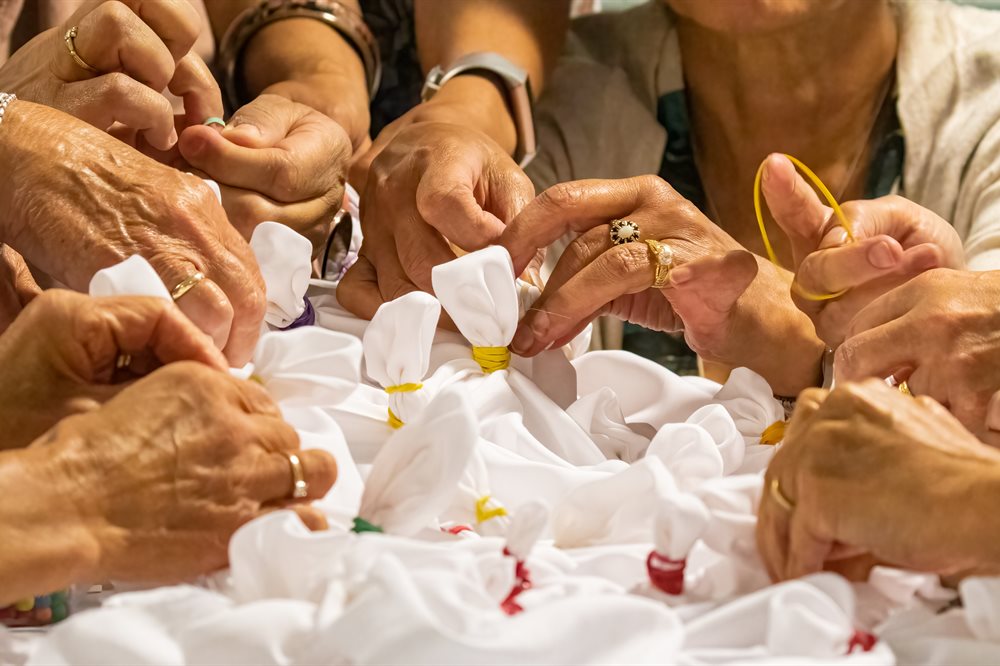 Many hands reaching into the middle of a table to help shape napkins