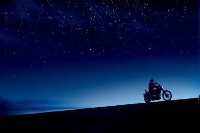 night time shot of a motorcycle driving along the horizon