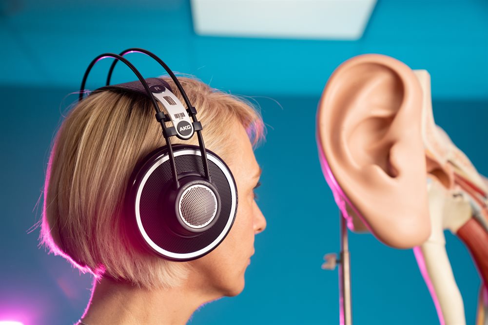 A participant wearing headphones adjacent an ear model