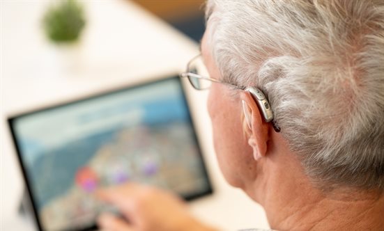 A participant with a hearing aid undertaking a study on a tablet