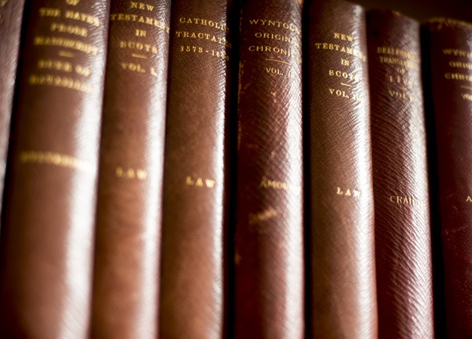 Photograph of a row of thick, brown hardback books with gold writing on the spines.