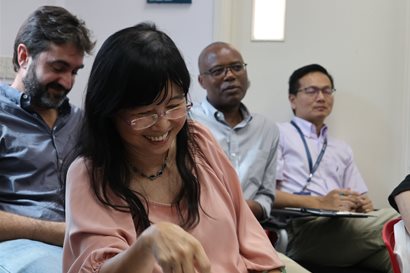 One workshop participant, in a pink top, laughing with her head lowered while others look on