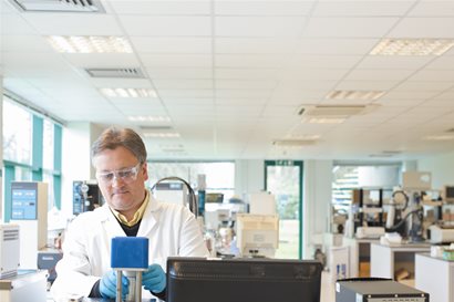 Scientist wearing goggles using a machine in a lab