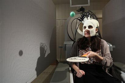 Female wearing brain scanner and using ping pong paddle with ball