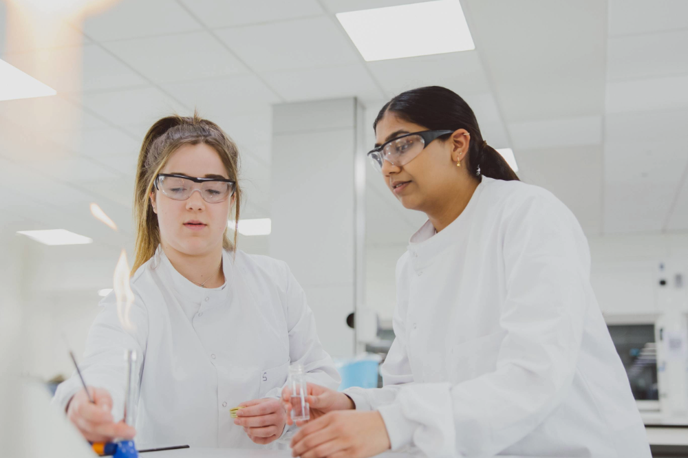 Two undergraduate students using a Bunsen burner in the STEM lab