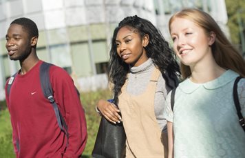 A group of three undergraduate students walking past George Green Library on University Park campus