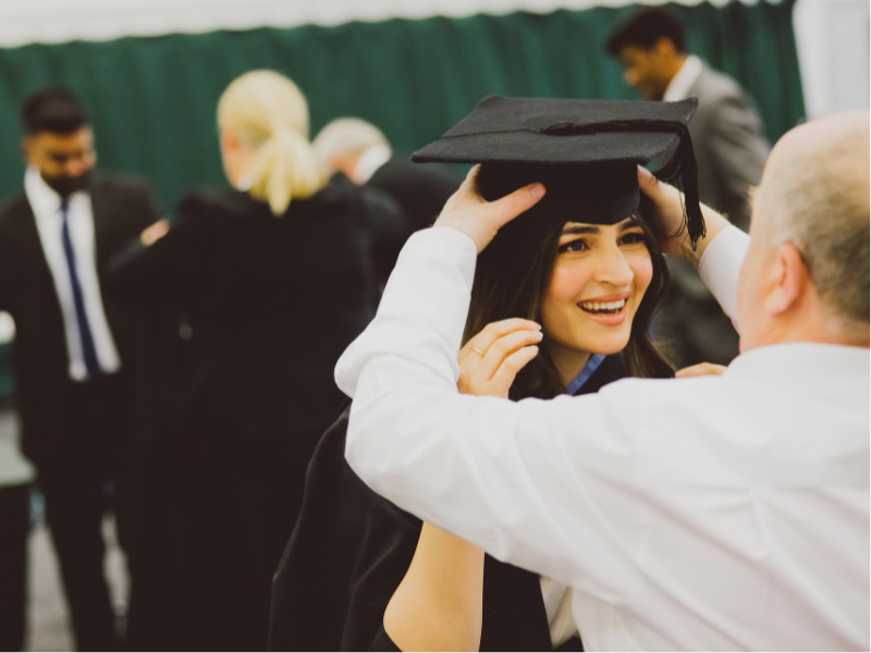 Photograph of a graduate trying on their cap