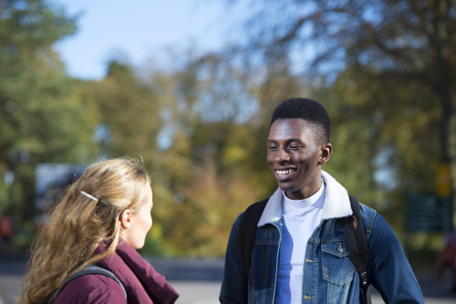 Male and female student talking and smiling outside