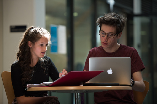 A male and female student sat at a table with laptops