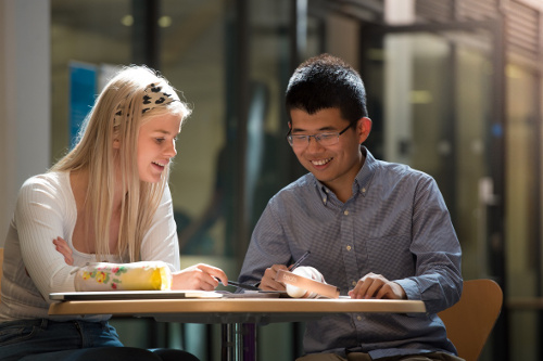 A male and female student in a mentor meeting over coffee
