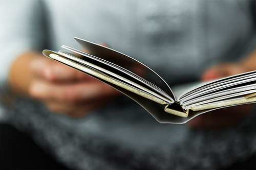 A close up of a person holding a book open to read