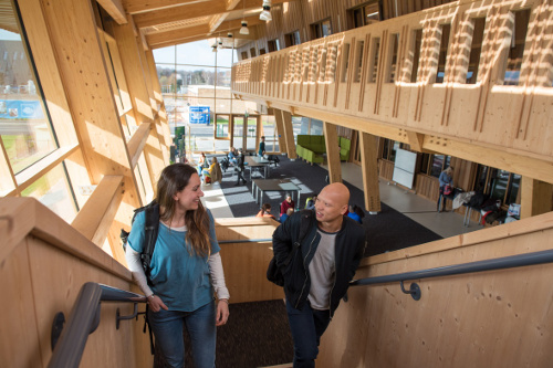 Students and staff talking on a staircase in the GSK Carbon Neutral Laboratory on Jubilee Campus