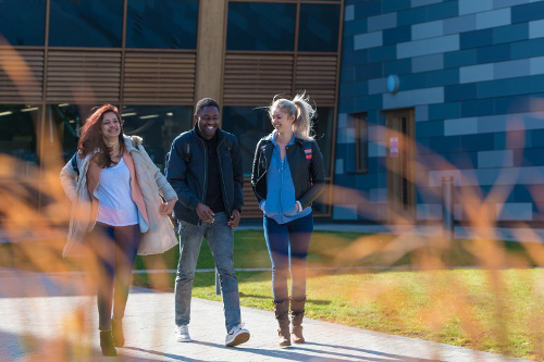 Three smiling students walking