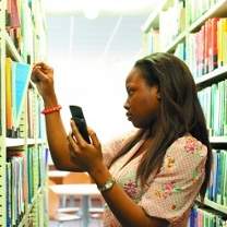 Student using mobile phone to find books in the library