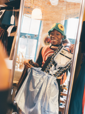 Brightly dressed student looking in mirror clothes shopping