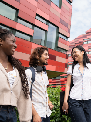 Three students walking outside on Jubilee Campus talking and smiling