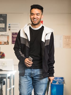 Male student carrying phone, smiling