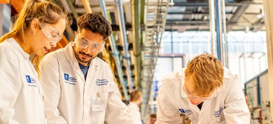 Three students in white coats working in a laboratory