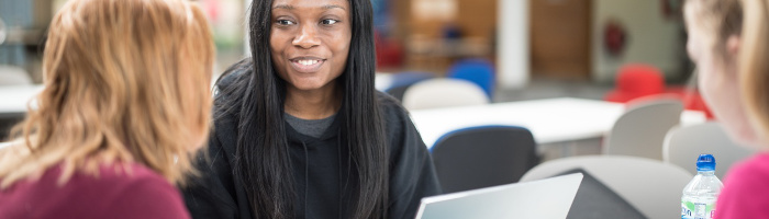Photograph of three students in discussion, smiling