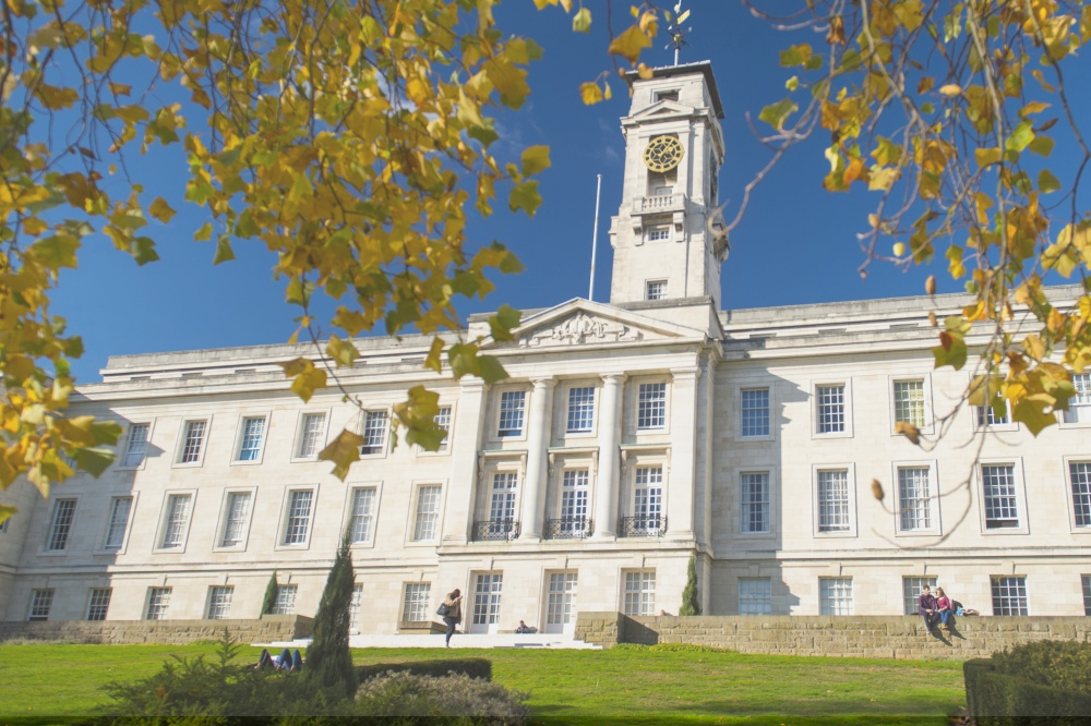 The Trent Building at University Park Campus, with a grassy lawn and trees in the sunshine