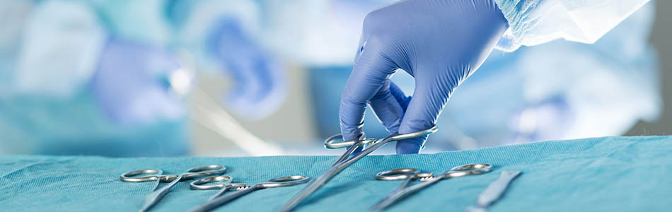 Veterinary surgeon picking up forceps off a tray of veterinary medicine tools