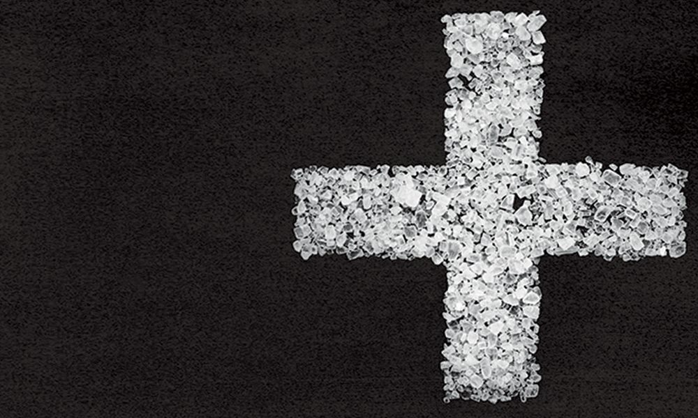 White cross made up of empty pill packets on black background